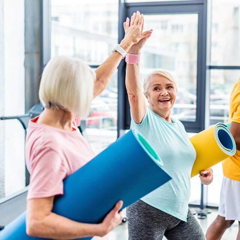 smiling senior multiethnic sportspeople fitness mats taking high fives